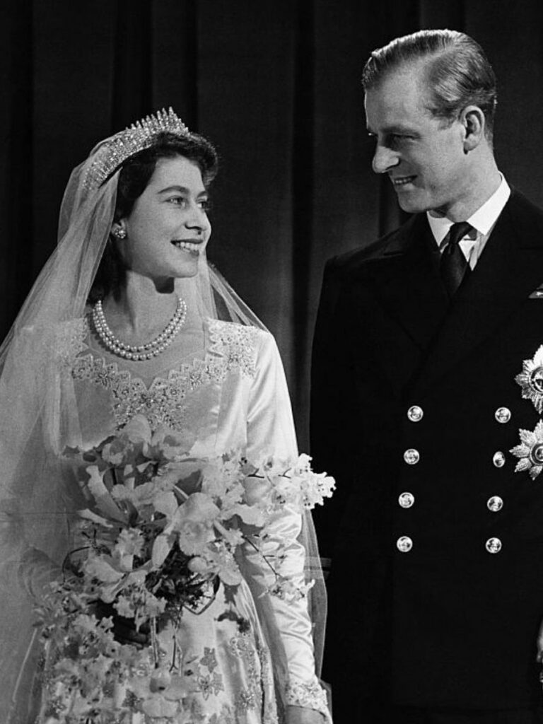 Black and white photo of bride and groom Queen Elizabeth II and Phillip, Duke of Edinburgh on their wedding day. Queen Elizabeth wears the Queen Mary British Royal Tiara.