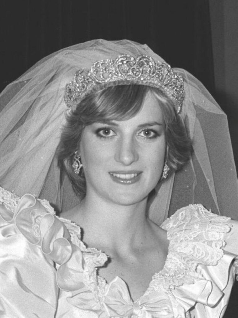 Black and white photo of woman looking at camera wearing wedding gown and elaborate tiara