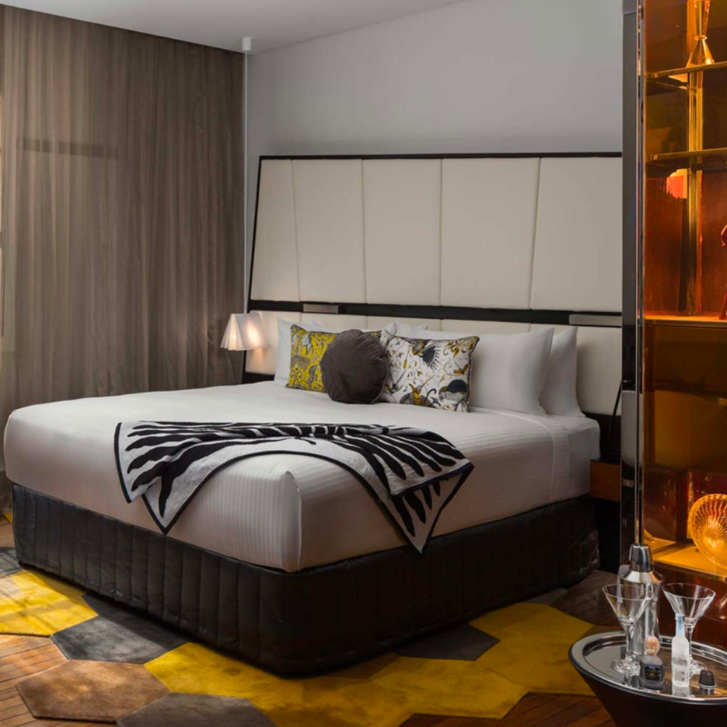 A luxurious hotel room with king sized bed on yellow patterned rug